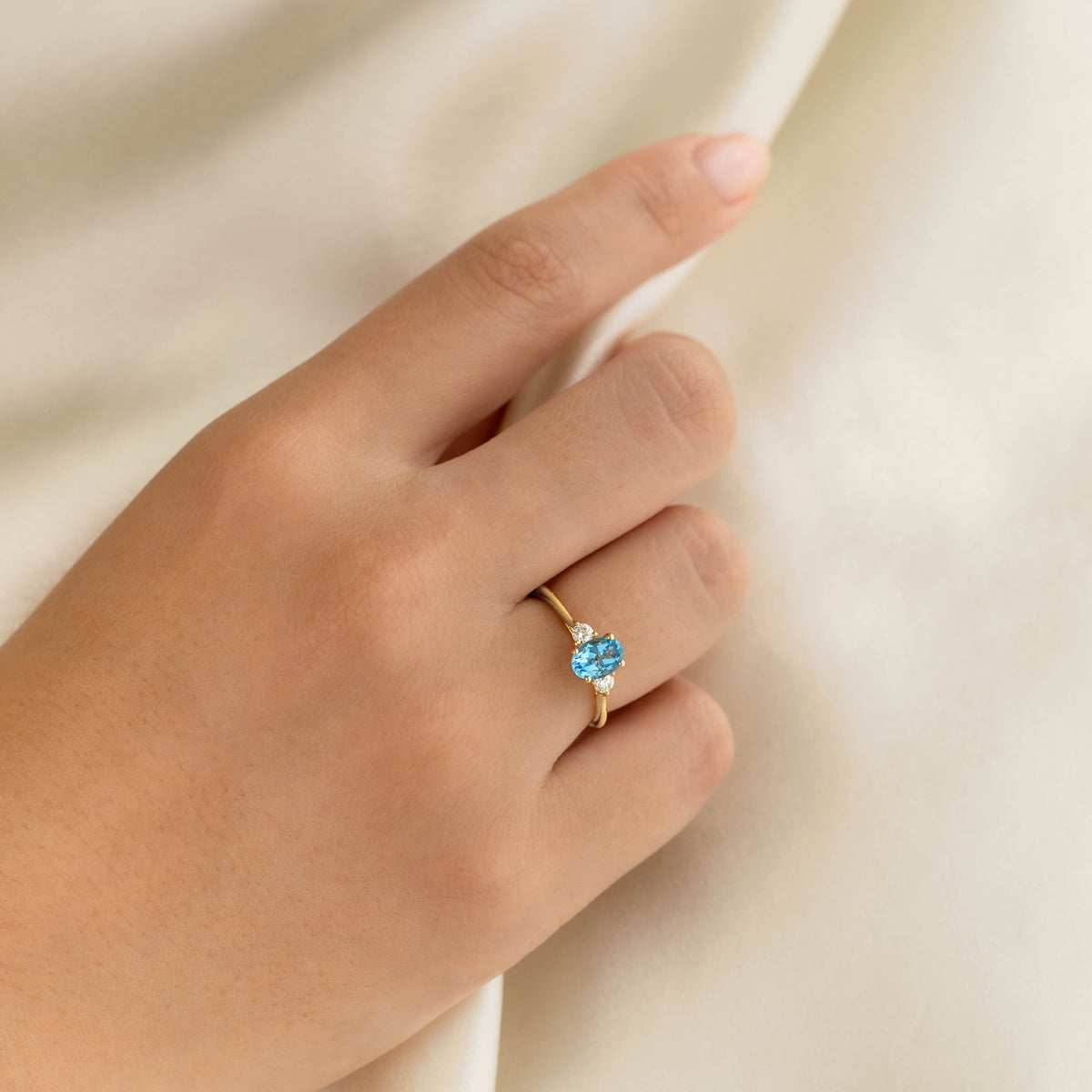 Swiss Blue Topaz and Diamond Ring 14k Gold - Kindra worn on hand against soft cream fabric background