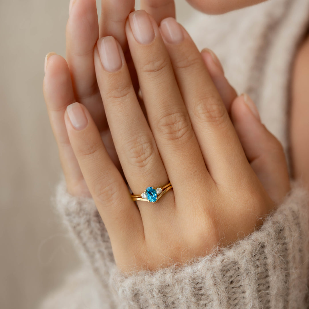 Close-up of hand wearing Swiss Blue Topaz and Diamond Ring 14k Gold - Kindra with soft beige sweater background