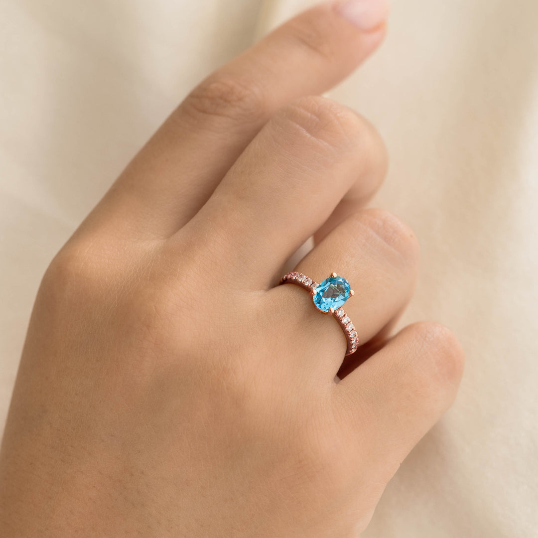 Oval Swiss Blue Topaz and Diamond Ring Rose Gold - Minette worn on hand against a soft cream background