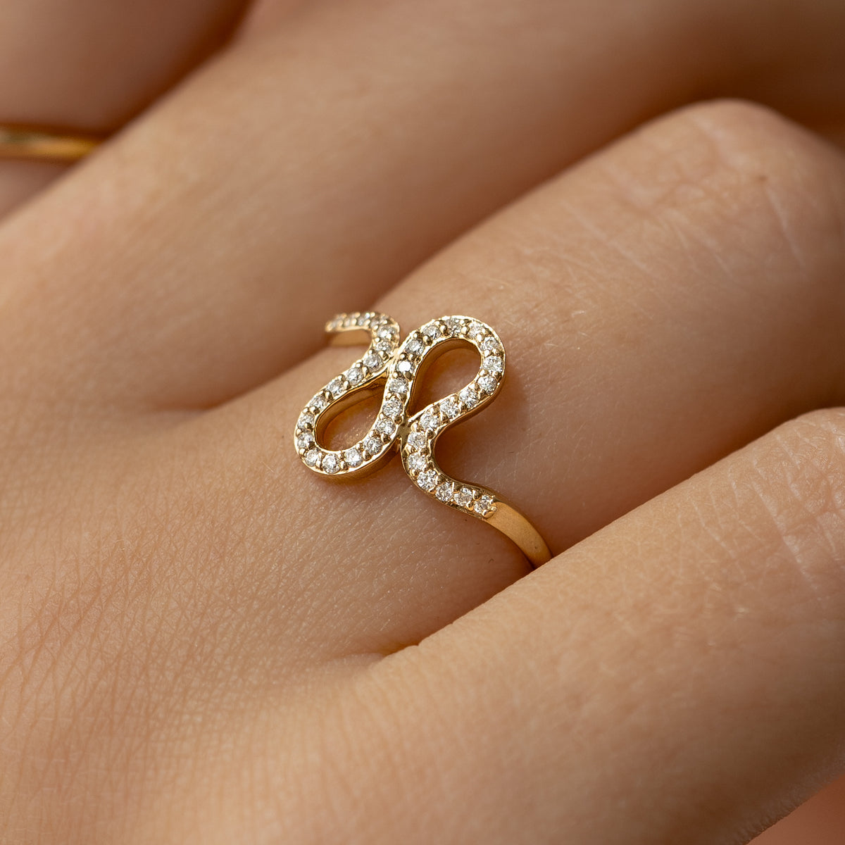 Close-up of a hand wearing the Diamond Squiggle Ring 14k Gold with pavé set brilliant diamonds on a gold band