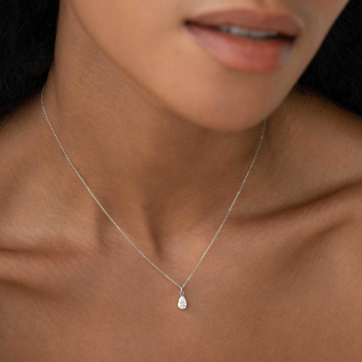 Close-up of a woman wearing the Pear Cut Diamond Pendant Necklace White Gold - Oline on a delicate 14k chain