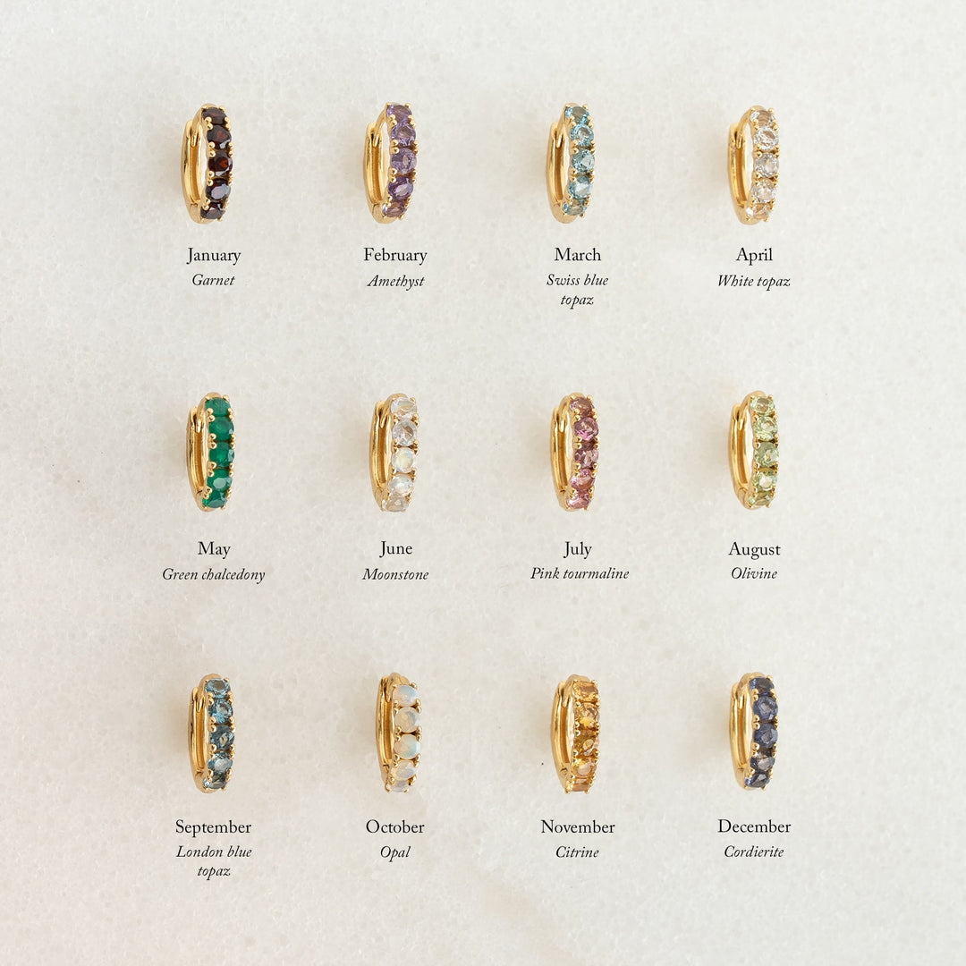Row of gold vermeil huggie earrings with February Birthstone Huggie Earrings - Amethyst featuring purple gemstones on cream background