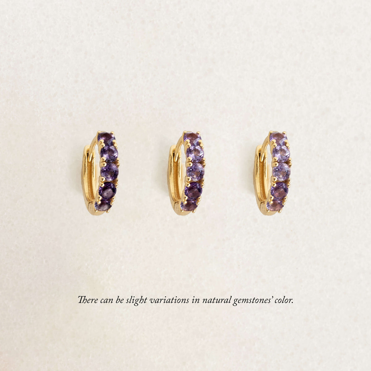 February Birthstone Huggie Earrings - Amethyst with gold vermeil setting on a soft beige textured background