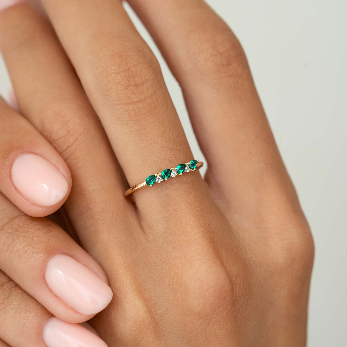Close-up of a hand wearing a May Birthstone Pear Ring 14k Gold - Emerald and Diamond with green and white stones