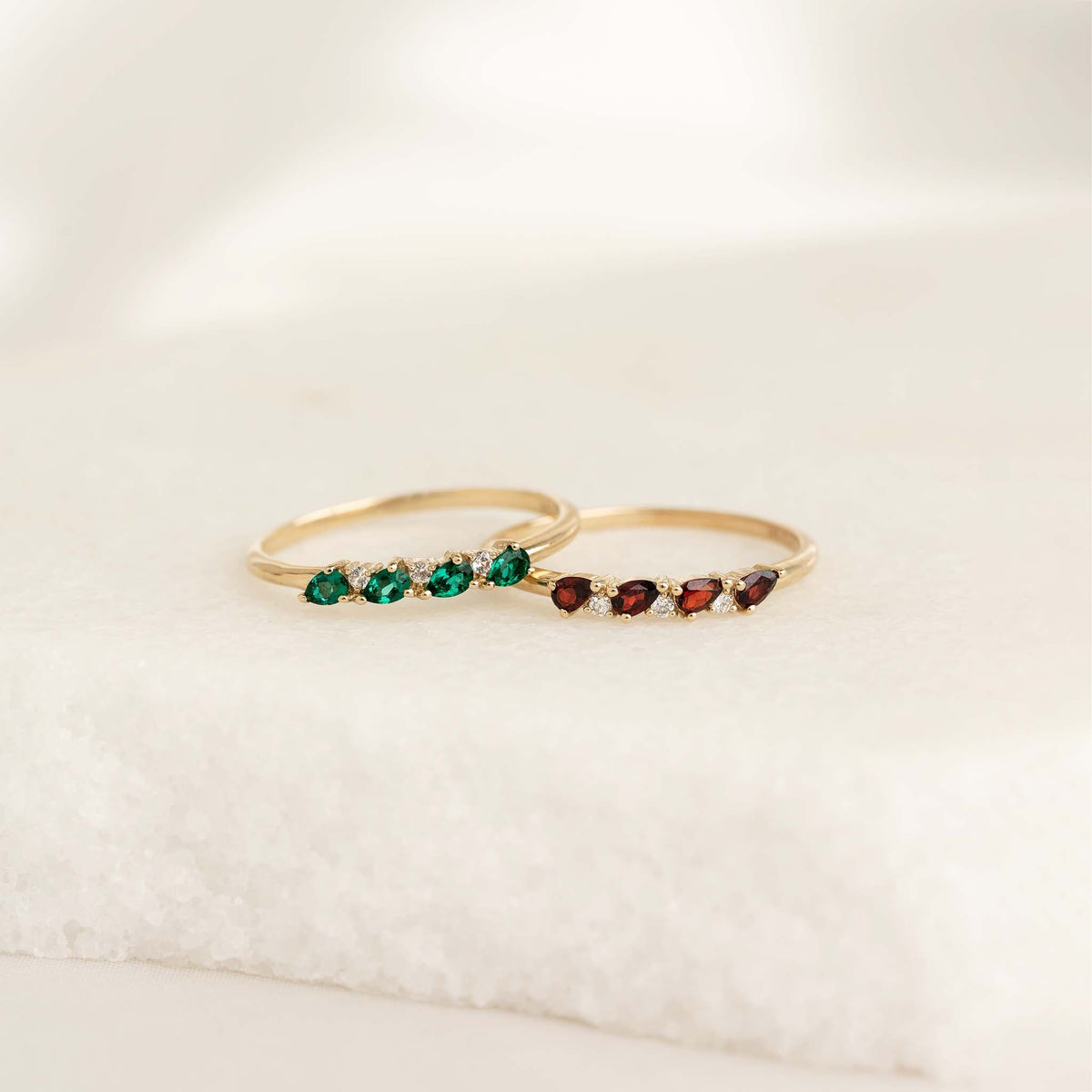 Close-up of two delicate gold rings with pear cut gemstones including May Birthstone Pear Ring 14k Gold - Emerald and Diamond
