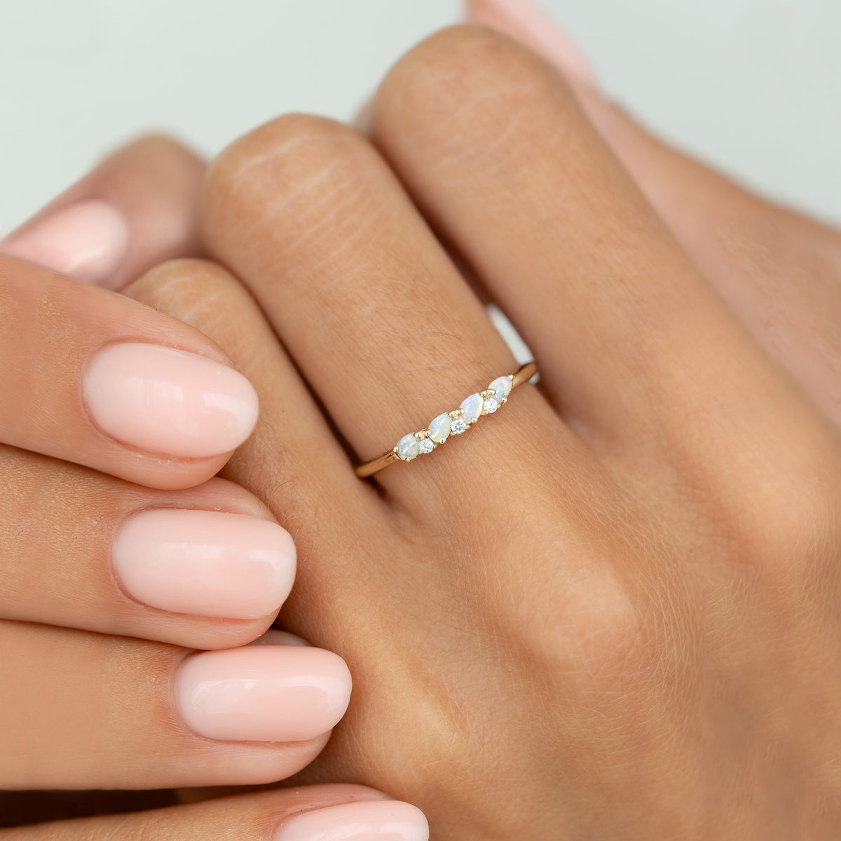 Close-up of hand wearing October Birthstone Pear Ring 14k Gold - Opal and Diamond with polished nails on neutral background