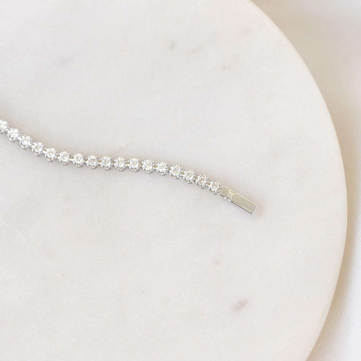 White Gold diamond tennis bracelet on a plate and warm background