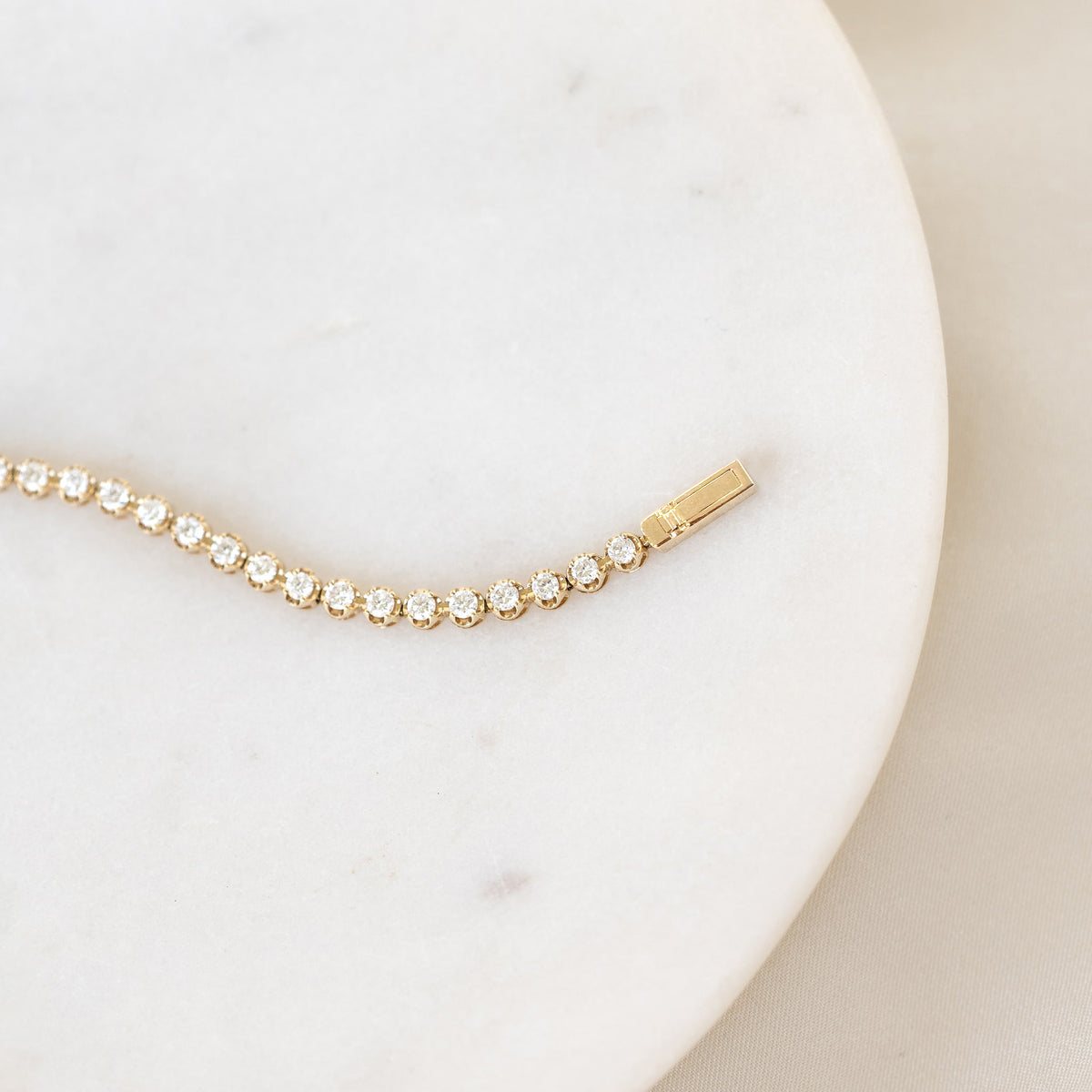 Close-up of Diamond Tennis Bracelet 14k Gold (1.501 ct tw) - Mirella laid on a white marble surface