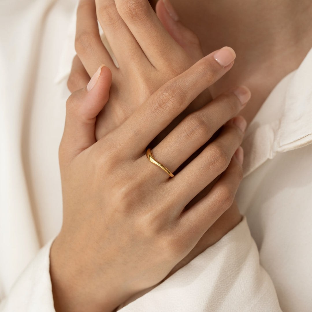 Close-up of hands wearing the Organic Wavy Ring - Nyssa in gold vermeil with a soft beige blouse background
