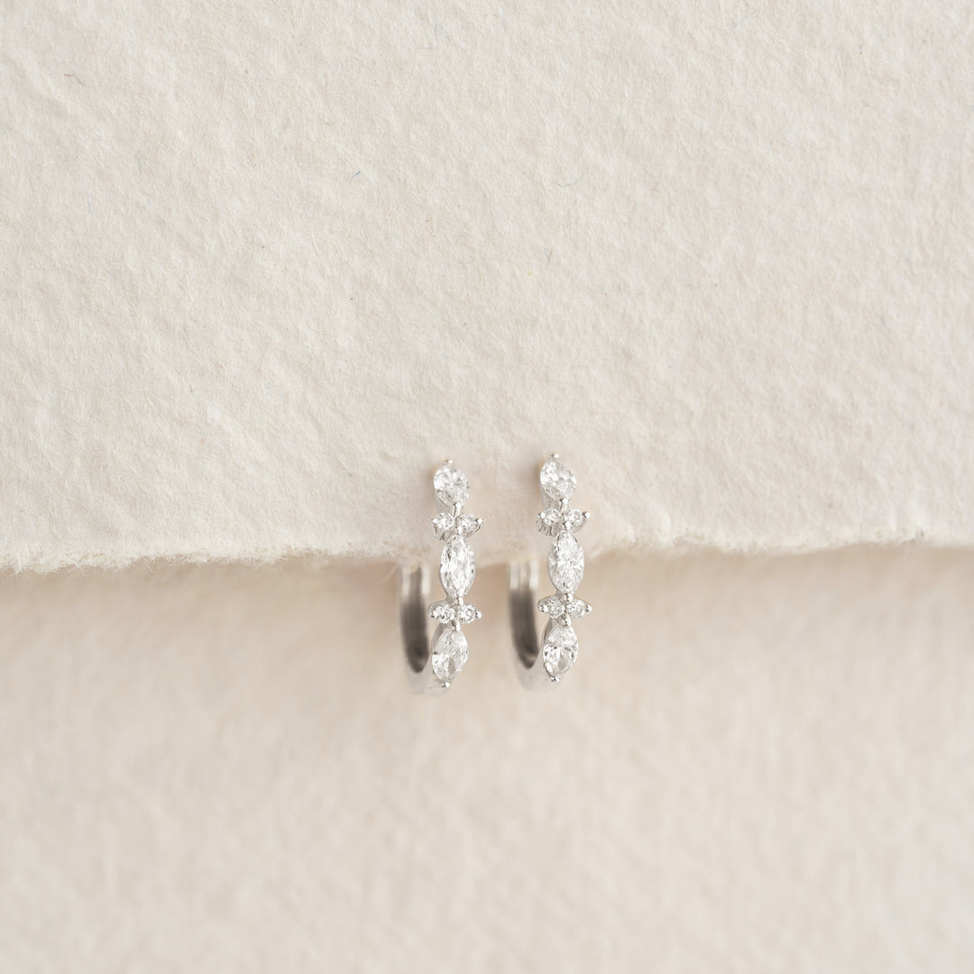 Close-up of Marquise and Round Diamond Huggie Earrings White Gold - Zoya on textured neutral background