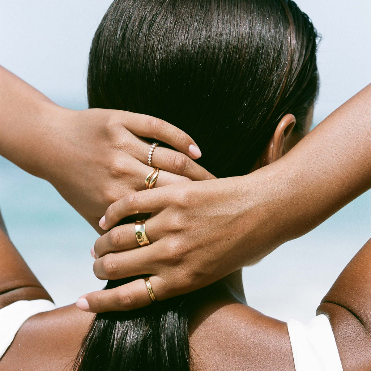 Woman with dark hair wearing the Organic Wavy Ring - Nyssa on her finger by the beach in natural light