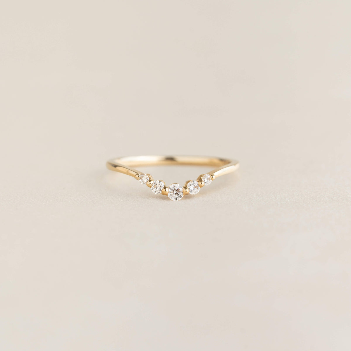 Close-up of the Graduated Diamond V Ring 14k Gold - Liora with five diamonds on a delicate gold band on a neutral background