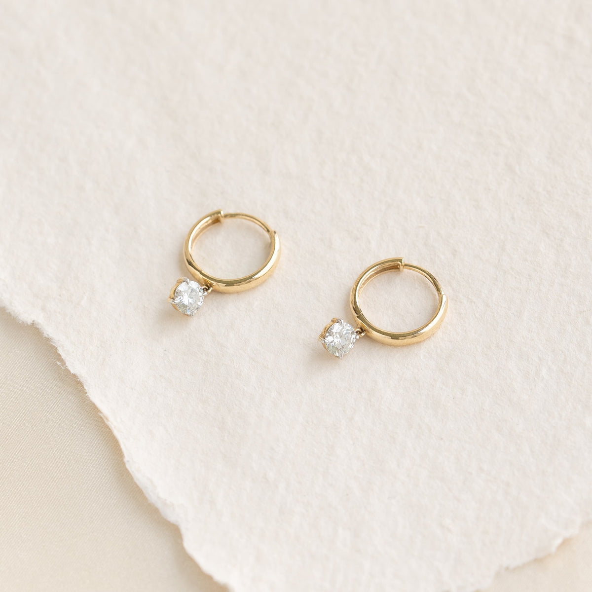 Stylish yellow gold huggie earrings with diamond embellishments, featuring a classic hoop design.