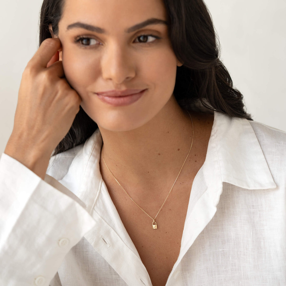 Model wearing a delicate Yellow Gold necklace with a small padlock-shaped pendant, styled with a white collared shirt.