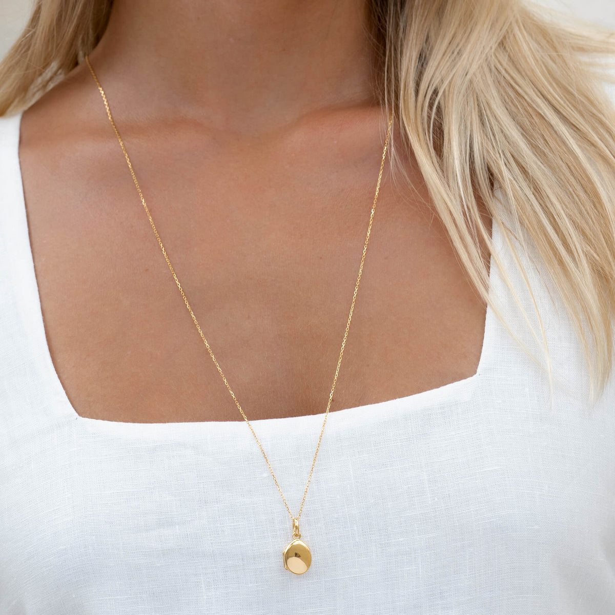 Gold locket necklace on model