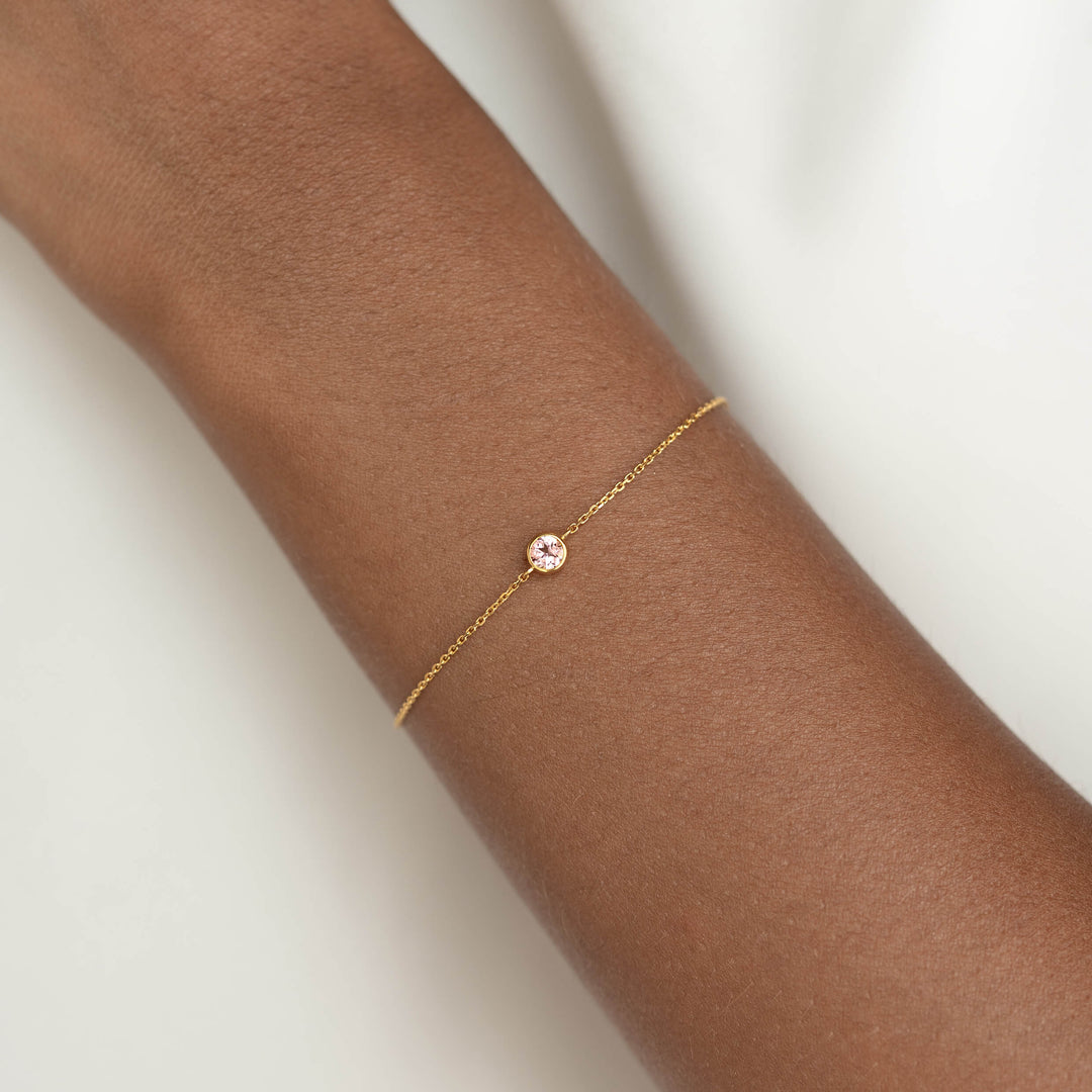 Delicate Gold Vermeil chain bracelet with a small round Light pink tourmaline gemstone centerpiece, worn around a woman's wrist.