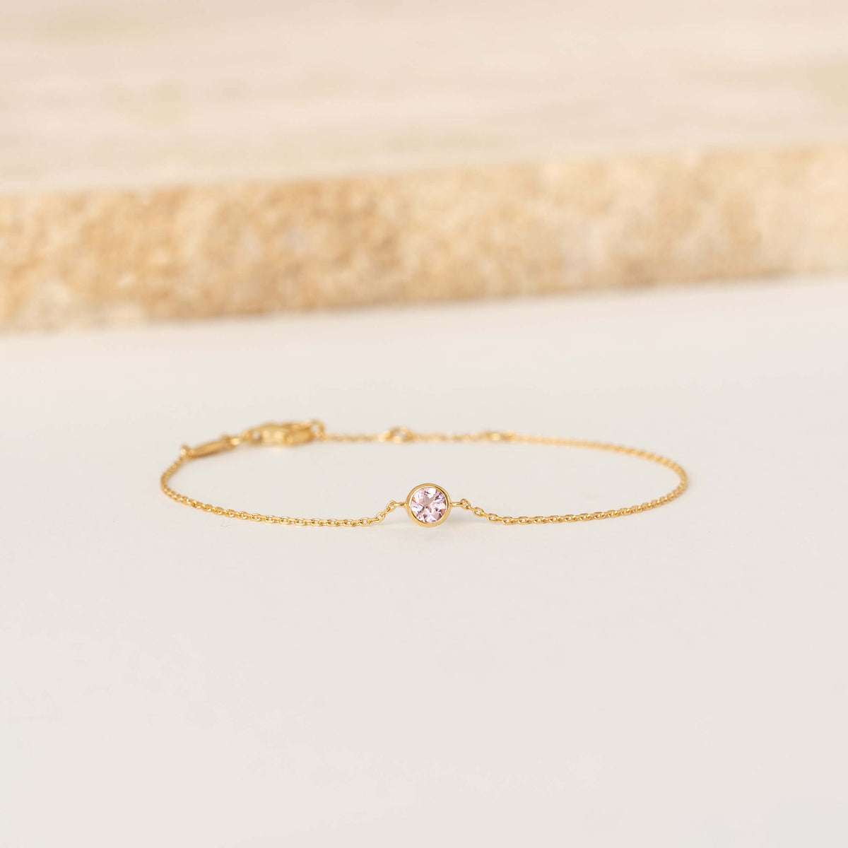 Delicate Gold Vermeil chain bracelet featuring a small round Light pink tourmaline gemstone centerpiece, laid flat on a light-colored surface.