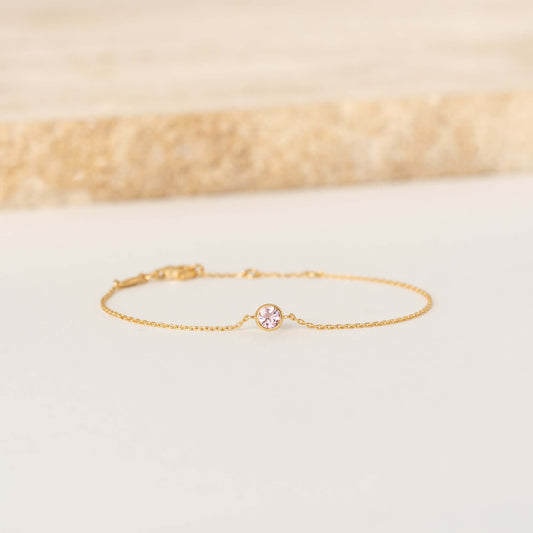 Delicate Gold Vermeil chain bracelet featuring a small round Light pink tourmaline gemstone centerpiece, laid flat on a light-colored surface.