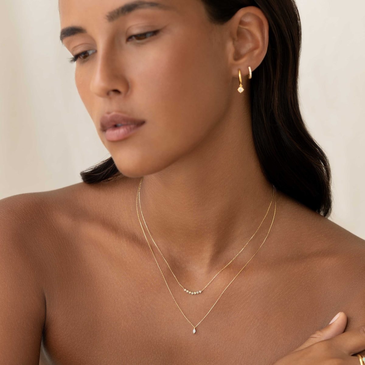 Woman wearing October Birthstone Necklace 14k Gold - Opal layered with delicate gold earrings on a neutral background