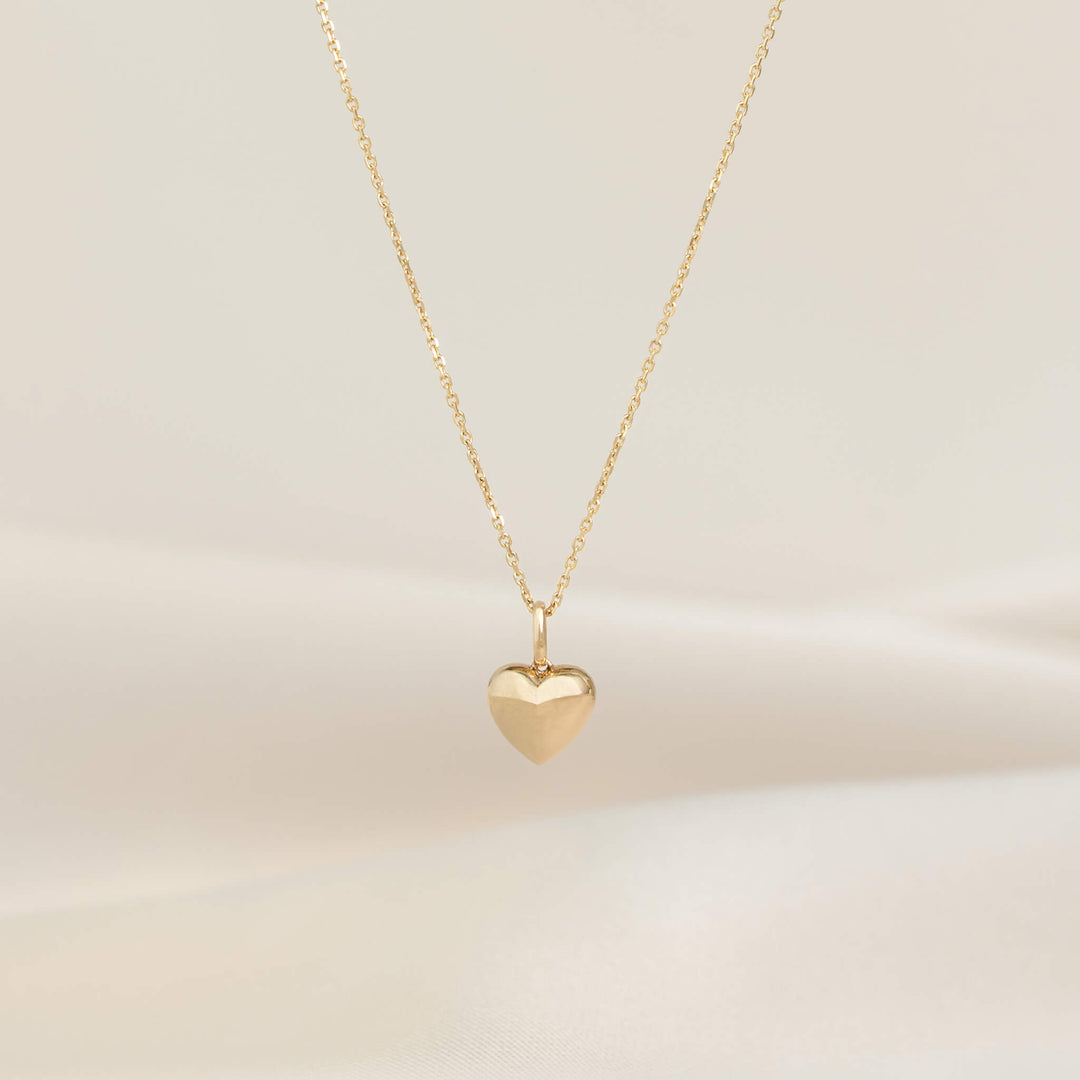 Yellow Gold necklace with a polished heart-shaped pendant, displayed on a delicate chain against a soft neutral background.