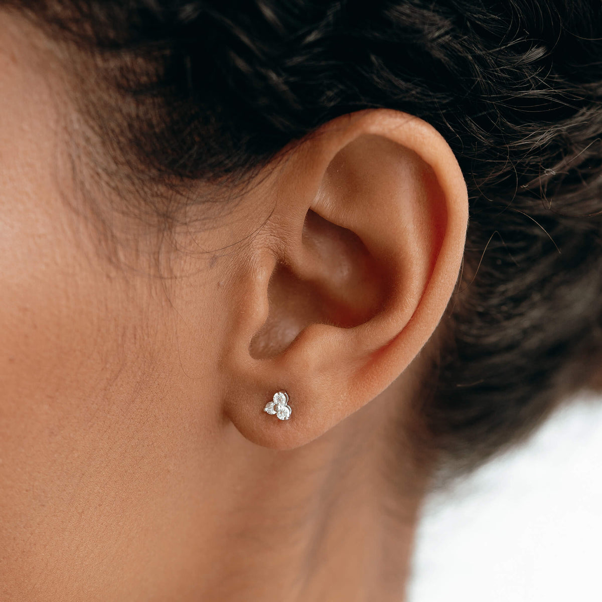 Close-up of ear wearing 14k White Gold Diamond Stud Earrings - Trillium with three lab grown diamonds in flower design